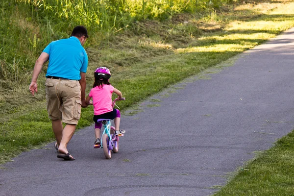 Kind leren om te rijden een fiets met vader Rechtenvrije Stockafbeeldingen
