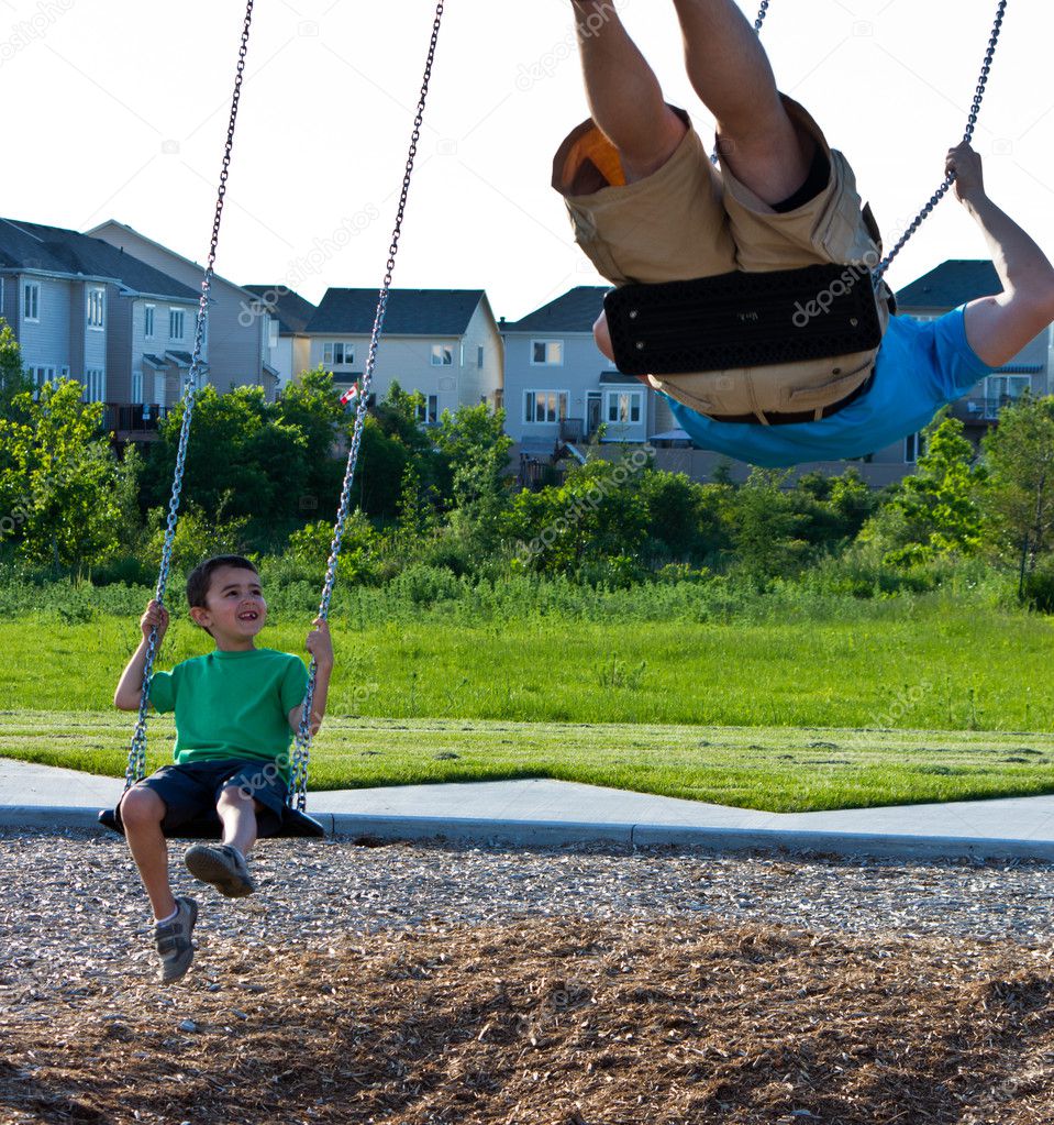 Child and father playing on the swing set