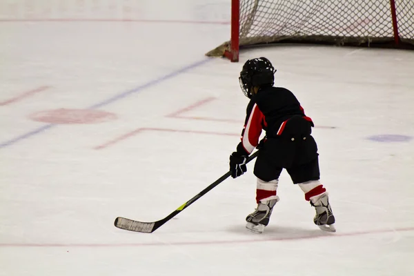 Child skating and playing hockey in an arena — Stock Photo, Image