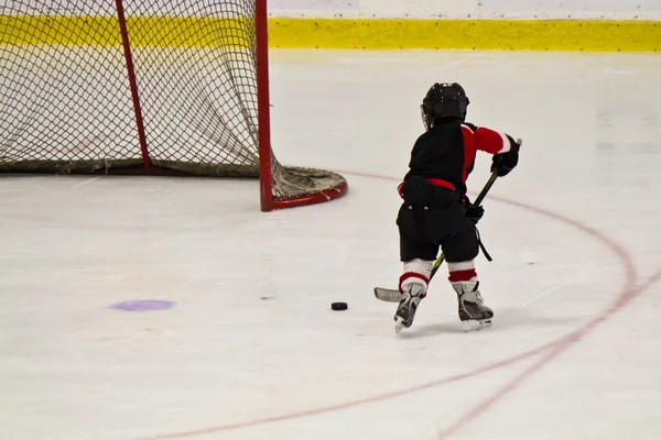 Kind schaatsen en spelen hockey in een arena — Stockfoto