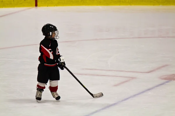 Child skating and playing hockey in an arena — Stock Photo, Image