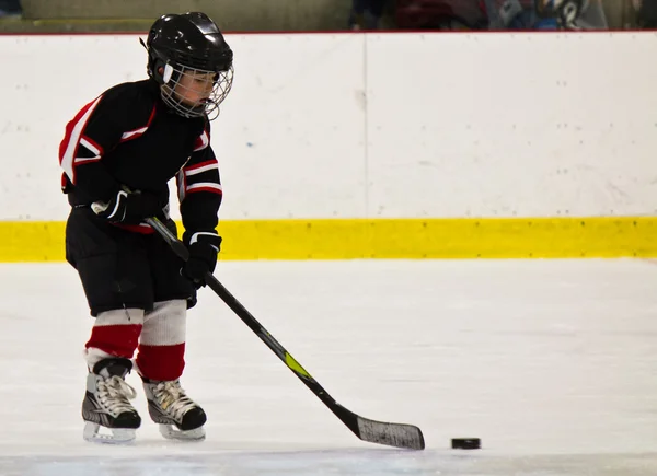 Kind schaatsen en spelen hockey in een arena — Stockfoto