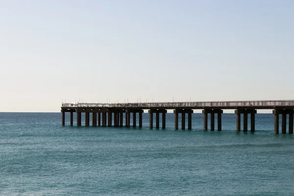 Ocean fishing pier stretchs over calm seas — Stock Photo, Image