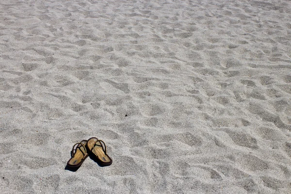 Sandalias chanclas en la playa de arena — Foto de Stock