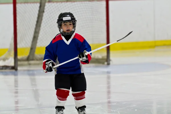 Petit garçon jouant au hockey sur glace dans une arène — Photo