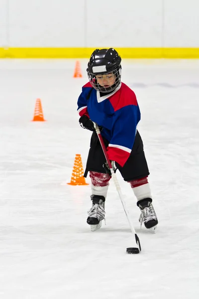 Ragazzo che pattina con il disco all'allenamento di hockey su ghiaccio — Foto Stock