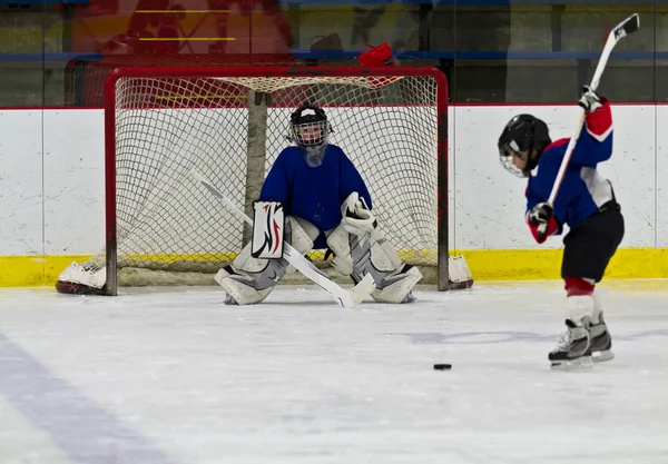 Ijshockeyspeler schiet de puck op het net Stockfoto