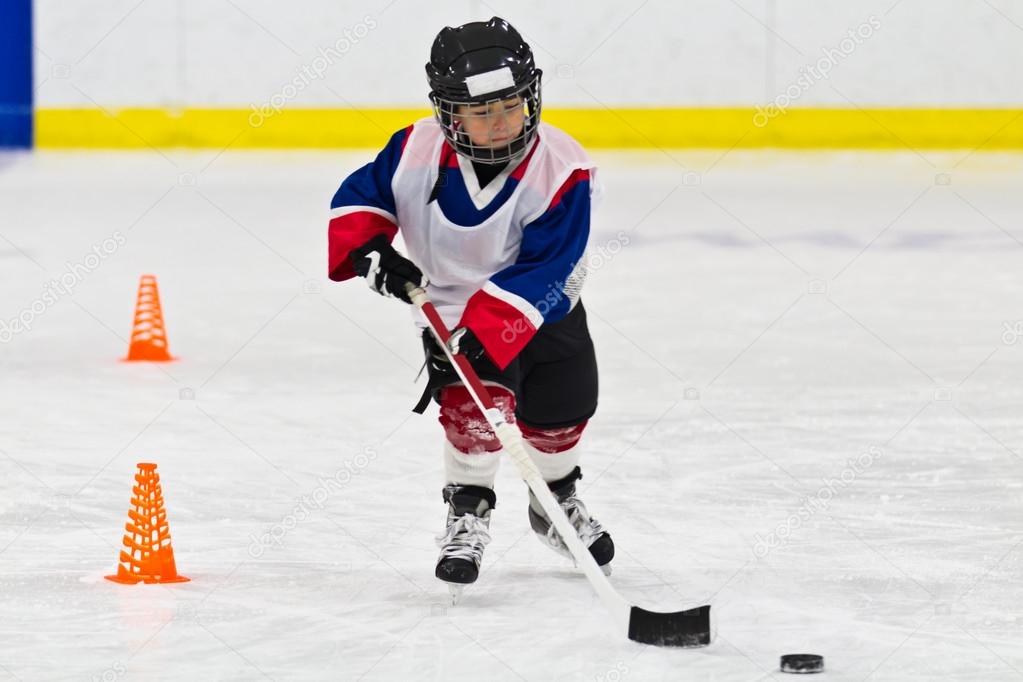 Child skating with a puck at ice hockey practice