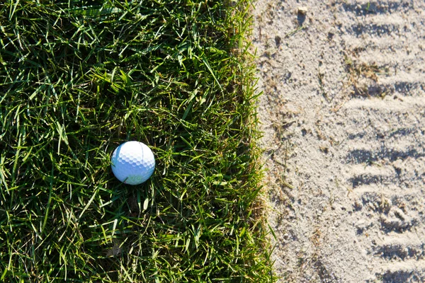 Golf ball op de rand van de zand bunker — Stockfoto