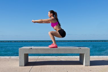 Hispanic woman doing squats by the water clipart