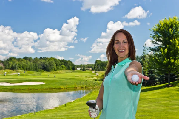 Mulher mostrando uma bola de golfe nos links — Fotografia de Stock