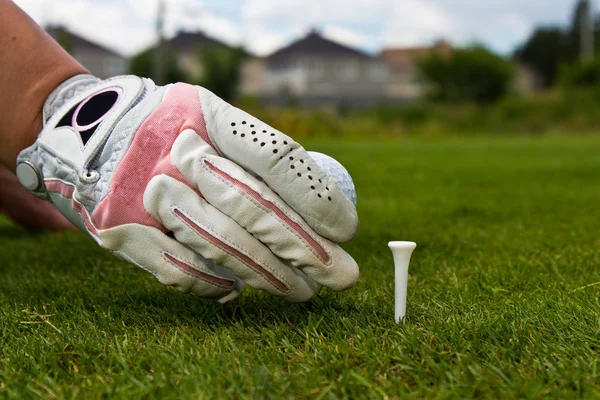 Primer plano de una mano enguantada de una golfista colocando una pelota de golf o — Foto de Stock