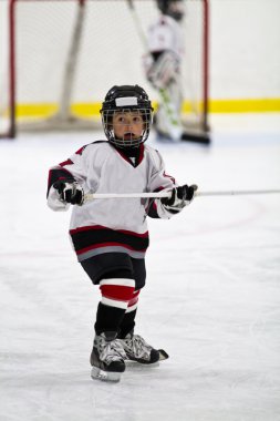 Çocuk arenada hokey oynuyor.