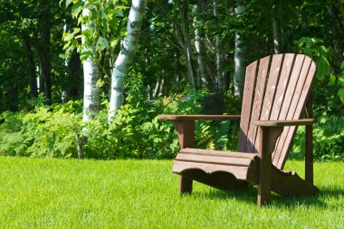 Wooden Adirondack summer lawn chair outside on the green grass clipart