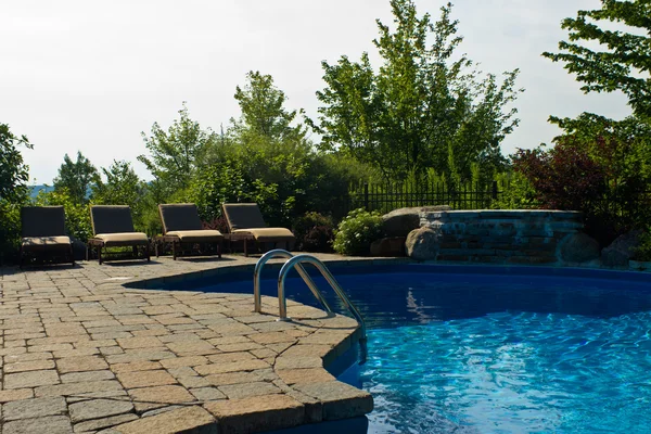 A luxurious outdoor swimming pool with a group of deck chairs — Stock Photo, Image