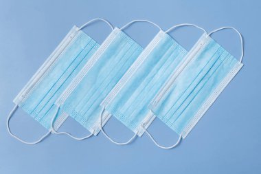Several medical protective masks lying in a row on a light blue background