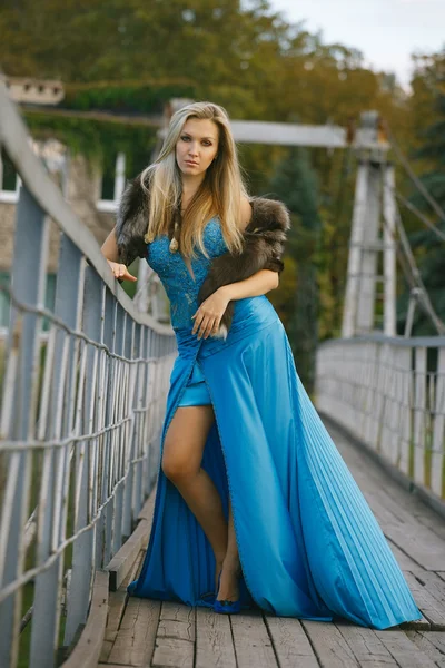 Beautiful blond girl standing on the bridge in the park. — Stock Photo, Image