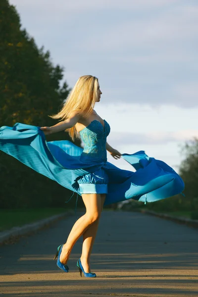 Elegant woman in blue dress whirls and enjoying life in the park — Stock Photo, Image