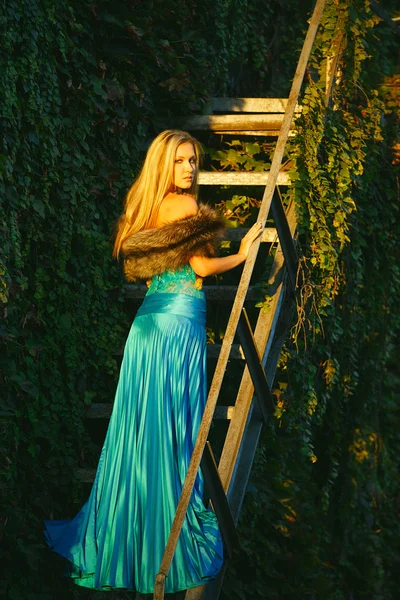 Beautiful blond girl standing on the stares in the park — Stock Photo, Image