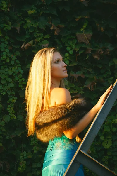 Beautiful blond girl standing on the stares in the park — Stock Photo, Image