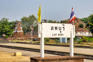 Lopburi tren istasyonunda Lop Buri tabelası. Wat Nakhon Kosa, Lopburi, Tayland 'daki antik harabelerin önünde.