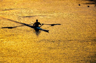 Günbatımında Tiber nehrinde kano talimi yapan sporcu, Roma, İtalya