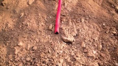 İnşaat sırasında yerden kanalizasyon borusu çıkarılmış. Binanın altından çıkarılan kablo kanalı yapım aşamasında. İnşaat alanı. Kırmızı kıvrımlı boru.