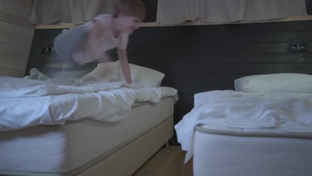 ベッドからベッドへ飛び跳ねるクレイジー子。子供は踊って楽しんでる — ストック動画