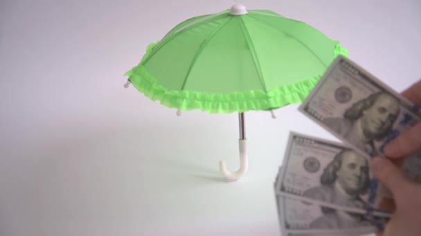 Les gros plans des mains sont considérés comme des billets en dollars. La main cache des dollars sous le parapluie. Concept de protection financière. Concentration sélective. Vidéo 4k de haute qualité — Video