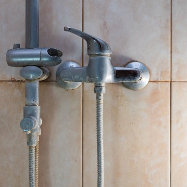 Duş musluğu. Musluk suyundan kaynaklanan yoğun kirlilik. Sudaki yüksek demir içeriğinden kaynaklanan sarı plaka. kireç ölçeği