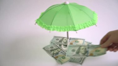 Yakın çekimler dolar banknotları olarak kabul edilir. El şemsiyenin altında dolar saklıyor. Finansal koruma kavramı. Seçici odaklanma. Yüksek kalite 4k video