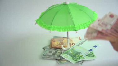 Eller yakın çekim. Faturaları say. Finansal çeşitlilik. Avro, dolar ve ruble. Birikimlerinizi farklı para birimlerine bölmek. Eller şemsiyenin altına para koysun. Konsept: