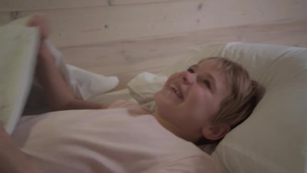 Het kind lacht terwijl het in bed ligt. Een grappig verhaaltje voor het slapen gaan. Tijd voor het slapen gaan. Gelach en plezier. — Stockvideo
