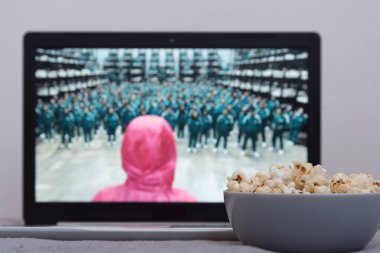 Fryazino, Moskova bölgesi, Rusya - 24 Ekim 2021: Dizüstü bilgisayarda Netflix serisi. Kalamar serisi oyunu. Patlamış mısır ön planda. En sevdiğiniz TV programını izlemek için her şey hazır.