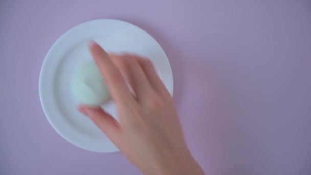 Ένα γυναικείο χέρι απλώνει ζαχαρωτά σε ένα πιατάκι. Θέα από ψηλά. Πολύχρωμα ζαχαρωτά. Λεπτές παστέλ αποχρώσεις — Αρχείο Βίντεο