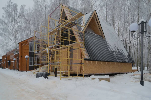 Zimní výstavba malého domku. Používají se dřevěné materiály. Jsou tu lešení.. — Stock fotografie