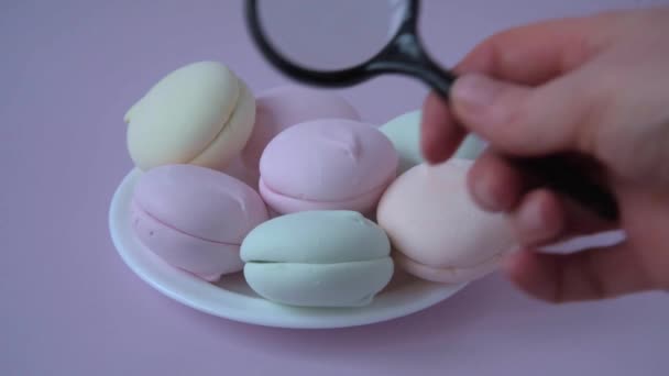 Denk aan marshmallows onder een vergrootglas. Het concept van het bestuderen van de samenstelling en kwaliteit van het product. Kleurrijke zoetigheden. — Stockvideo