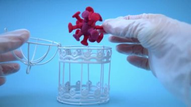 Tıbbi eldivendeki bir el, virüsü metal bir kafese yerleştirir. Coronavirüs 'ü yenme konsepti. Virüsün aşısı ve tedavisi. Bir doktorun işi, bir aşı üreticisinin işi, bir