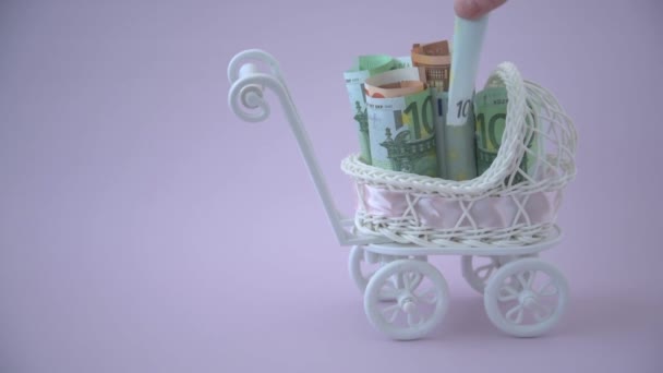 The hand adds euro bills to the baby stroller. The concept of costs for pregnancy and the appearance of a child in the family. Surrogacy. — Stock Video