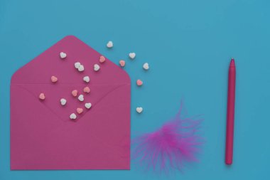 Mavi arka planda pembe bir zarf. Sevgililer Günü kartı için klasik renkler. Açık zarftan küçük renkli kalpler uçar. Yanında pembe bir kalem var. Tebrikler konsepti...