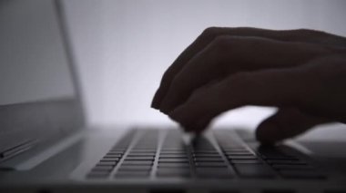 Karanlıkta hackerların elleri klavyede çalışır. Siber suçlar. Bir kişi geceleri bir dizüstü bilgisayarda çalışır. Gizem ve sır kavramı. Seçici odaklanma, yumuşak odaklanma