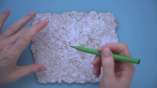 Womens hands draw a sign of reuse with a green felt-tip pen. Drawing on recycled paper. Reusable paper, background, texture. Care for the environment, ecology. — Stockvideo