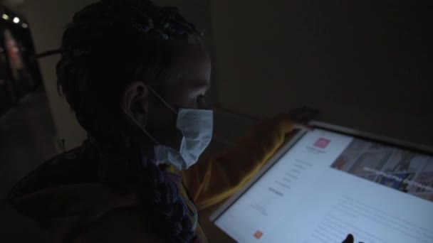 Una chica con máscara médica estudia un marcador interactivo. Un adolescente en un museo. Menú en formato electrónico en el restaurante. — Vídeos de Stock