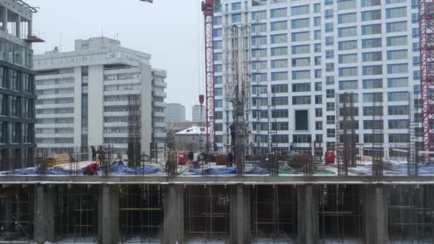 Baustelle eines mehrstöckigen Gebäudes. Winterzeit. Mehrere Arbeiter arbeiten auf der Baustelle. — Stockvideo