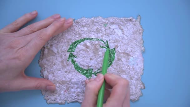Vrouwenhanden tekenen een teken van hergebruik met een groene viltstift. Tekenen op gerecycled papier. Herbruikbaar papier, achtergrond, textuur. Milieuzorg, ecologie. — Stockvideo