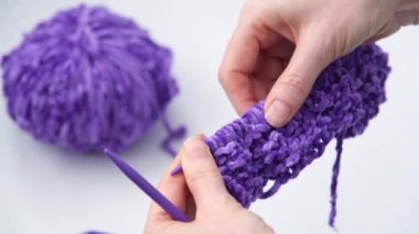 Kadın bağladığı şeyi inceliyor. Mor iplik rengi. Moda eğilimi rengi.