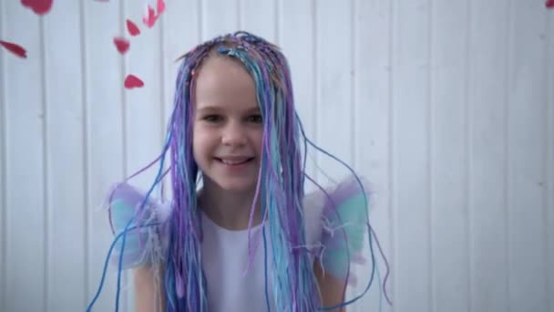 A teenage girl is dancing and having fun. The child tosses up confetti from his hearts. The concept of likes in social networks. The concept of congratulations on Valentines Day. A beautiful girl — Vídeo de Stock