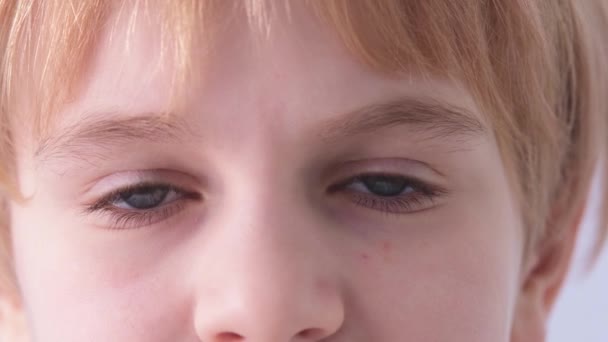 De ogen van de kinderen zijn close-up. Een kind met blauwe ogen kijkt in de camera. Schooljongen of schoolmeisje met rood haar. — Stockvideo