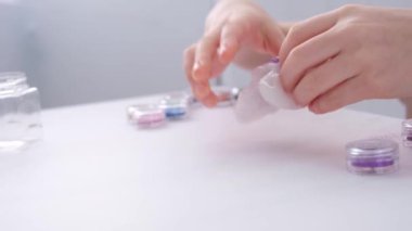 Çocukların elleri, yakın plan. Çocuk balçığa mor parıltılar ekliyor..