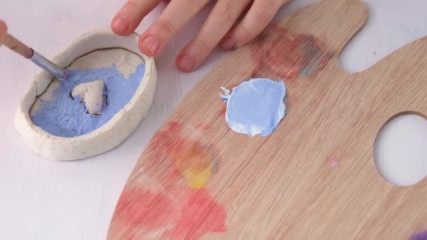 Un bambino prepara un regalo per San Valentino. Colorare il regalo con vernice blu. Lavori manuali. — Video Stock